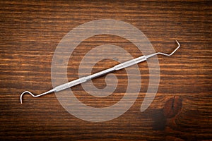 Dental hygienist instrument on wooden background. Learning and professionalism