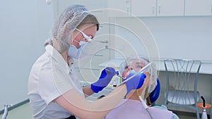 Dental hygienist makes ultrasonic teeth cleaning for young woman in dentistry.