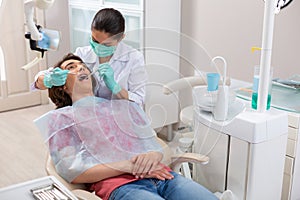 Dental hygienist putting a mirror into a patients mouth photo