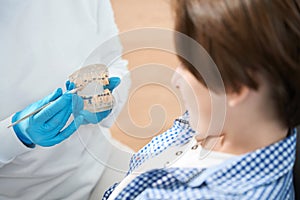 Dental hygienist teaches teenager methods of brushing teeth and braces