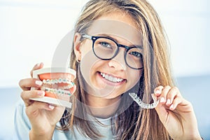 Dental invisible braces or silicone trainer in the hands of a young smiling girl. Orthodontic concept - Invisalign photo