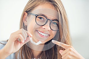 Dental invisible braces or silicone trainer in the hands of a young smiling girl. Orthodontic concept - Invisalign photo
