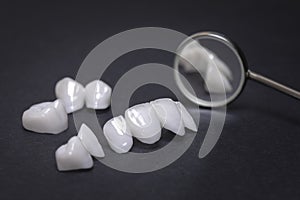 Dental mirror and zircon dentures on a dark background - Ceramic veneers - lumineers