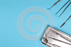 Dental mirrors and probes on a tray on a blue background.