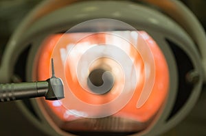 In the dental office - dental handpiece and dental bur close-up against the background of a medical lamp. Concept of dental