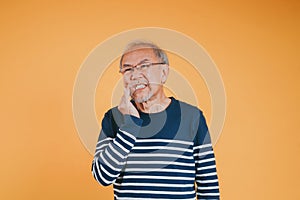 Dental pain. Portrait senior old man sad hand touching cheek suffering from toothache studio shot isolated on yellow background,