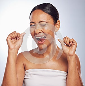 Dental, portrait or mature woman flossing teeth for beauty or wellness in studio on white background. Smile, self care