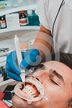 Dental practice, the dentist removes stones and hard plaque from the teeth with the help of ultrasound,patient with retractor and