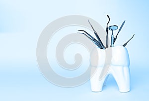Dental professional steel tools in tooth shaped holder on blue background. Set of metal medical equipment tools for