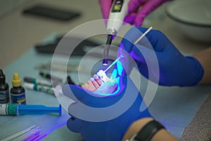 Prosthetics hands while working on the denture, false teeth, a study and a table with dental tools
