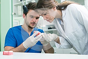 Dental prosthesis, dentures, prosthetics work. Prosthetics hands while working on the denture, false teeth, a study and a table wi