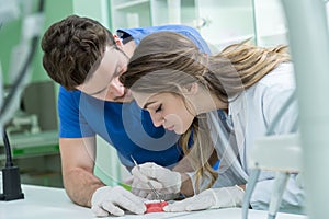 Dental prosthesis, dentures, prosthetics work. Prosthetics hands while working on the denture, false teeth, a study and a table wi