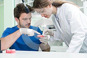 Dental prosthesis, dentures, prosthetics work. Prosthetics hands while working on the denture, false teeth, a study and a table wi