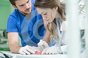 Dental prosthesis, dentures, prosthetics work. Prosthetics hands while working on the denture, false teeth, a study and a table wi