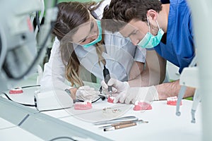 Dental prosthesis, dentures, prosthetics work. Prosthetics hands while working on the denture, false teeth, a study and a table wi