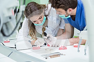 Dental prosthesis, dentures, prosthetics work. Prosthetics hands while working on the denture, false teeth, a study and a table wi