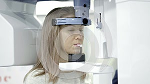 A dental X-Ray scanner making a panoramic radiograph of the jaw of young blonde woman.