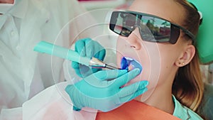 dental restoration in modern stomatological clinic for children, dentist using blue lamp