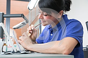 Technician in a dental laboratory applying ceramics to a prosthesis photo