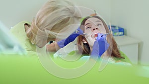 Dental technician examining patient teeth with dental instruments