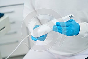 Dental technician holding intraoral camera, that showing to patients their dental health