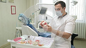 Dental technician holding plaster cast of jaws in dental office