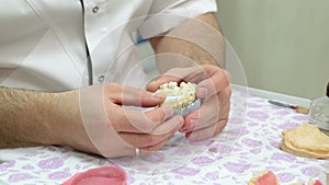 Dental technician looking at plaster cast of jaws while making denture in lab