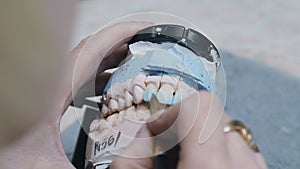 A dental technician paints a denture with a brush.