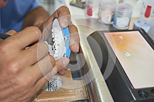 Dental technician using a brush with ceramic dental implants in