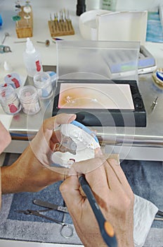 Dental technician using a brush with ceramic dental implants in