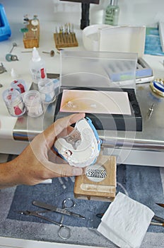 Dental technician using a brush with ceramic dental implants in