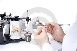 Dental technician working with articulator in dental laboratory