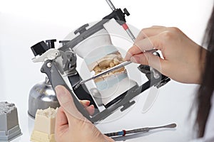 Dental technician working with articulator in dental laboratory