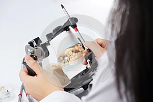 Dental technician working with articulator in dental laboratory