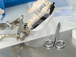 Dental technician is working with articulator in metal structure