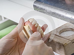 Dental technician is working with porcelain teeth in a cast mold