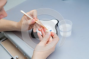 Dental technician works by brush with jaw model