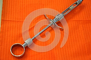 Dental tool isolated on orange surface, aspirating syringe, anesthetic cartridge photo