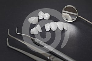 Dental tools and zircon dentures on a dark background - Ceramic veneers - lumineers