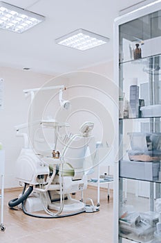 Dental treatment room with modern green chair, white tone. Orthodontic chair in small stomatology cabinet. Dental office