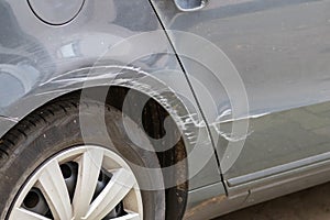 Dented car wing and fender with scratches and bumps after crash and car accident with hit-and-run driving and absconding shows nee