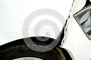 Dented and opening wound on a damaged white car photo