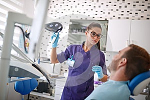 Dentist adjust reflector lamp before repairing teeth