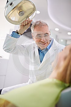 Dentist adjust searchlight to illumine patient's mouth