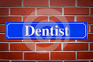 Dentist aid street sign on brick wall