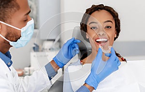 Dentist applying invisible aligner on female patient teeth