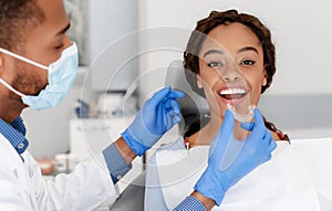 Dentist applying invisible aligner on female patient teeth photo