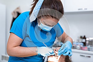Dentist appointment at a dental clinic, placing braces locks on the teeth and pulling the archwire to fix it photo