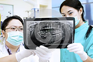 Dentist and assistant analysing x-ray at dental clinic