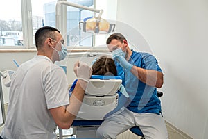 the dentist with the assistant carries out professional brushing of teeth of the patient.